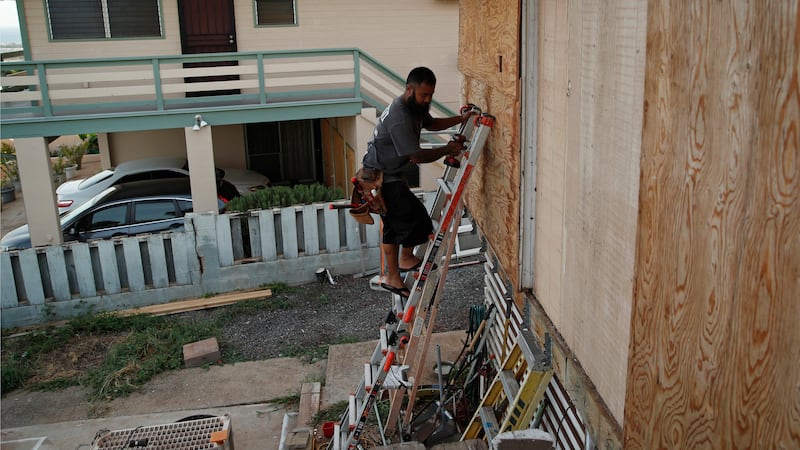 Kaipo Popa secures plywood to protect windows on a home in preparation for Hurricane Lane,...