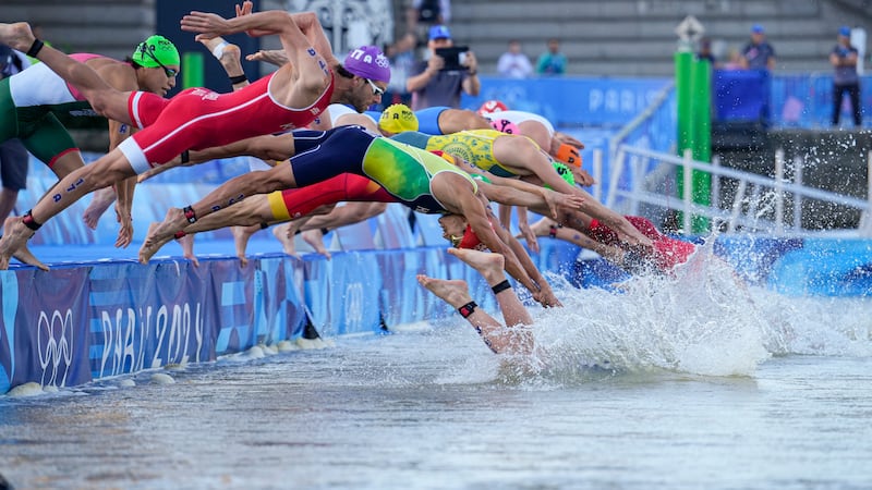 Athletes dive into the water for the start of the mixed relay triathlon at the 2024 Summer...