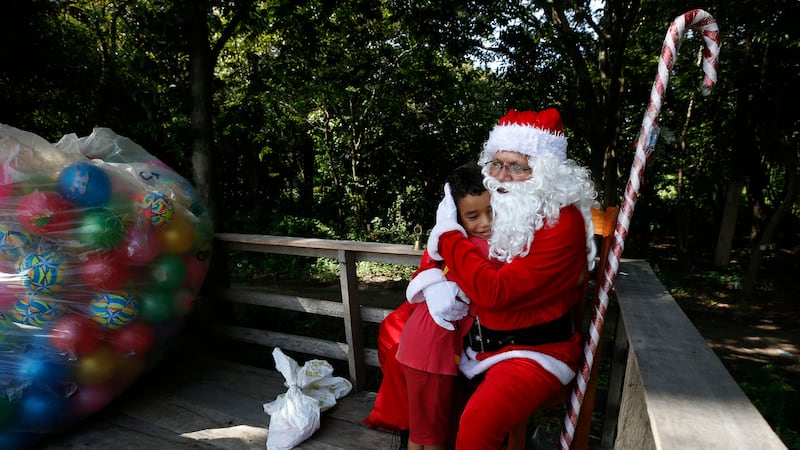 Jorge Barroso, dressed as Santa Claus, is embraced by a young resident after arriving on a...